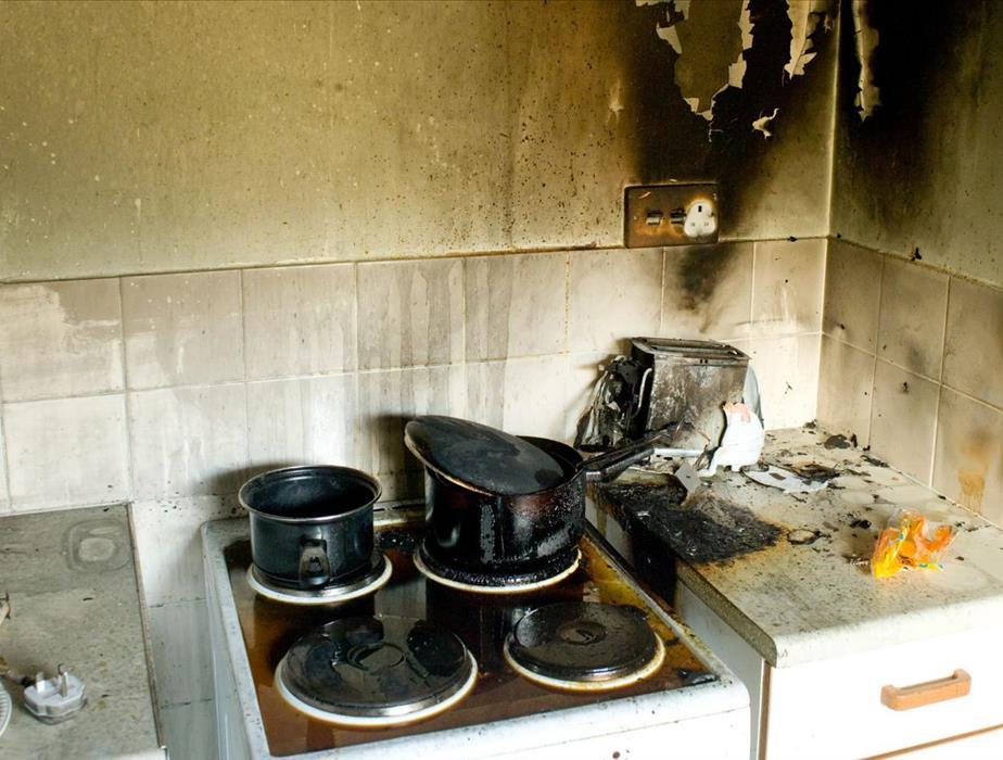 Stove with two black bots on top after a kitchen fire has burned everything.